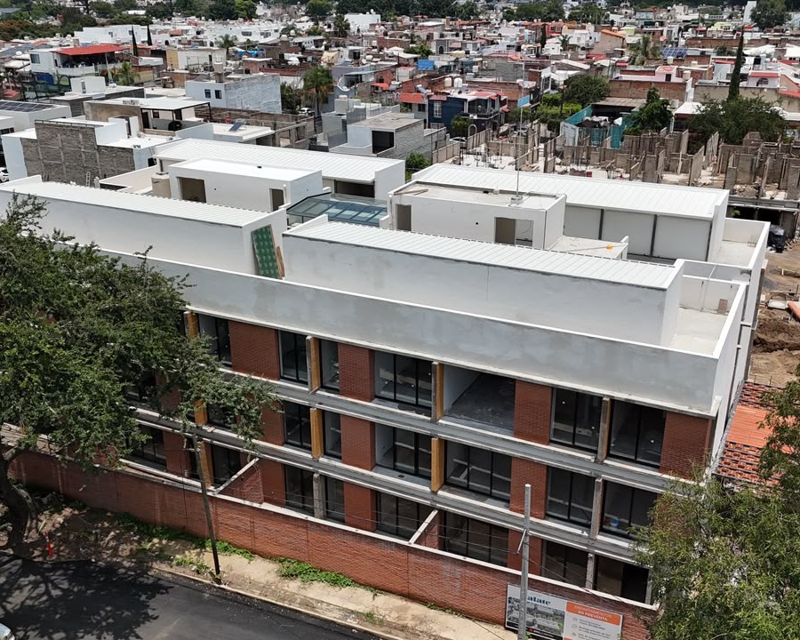 Vista aérea de la obra de Privada Zalate: el edificio de tabique y azoteas blancas levantándose entre el barrio