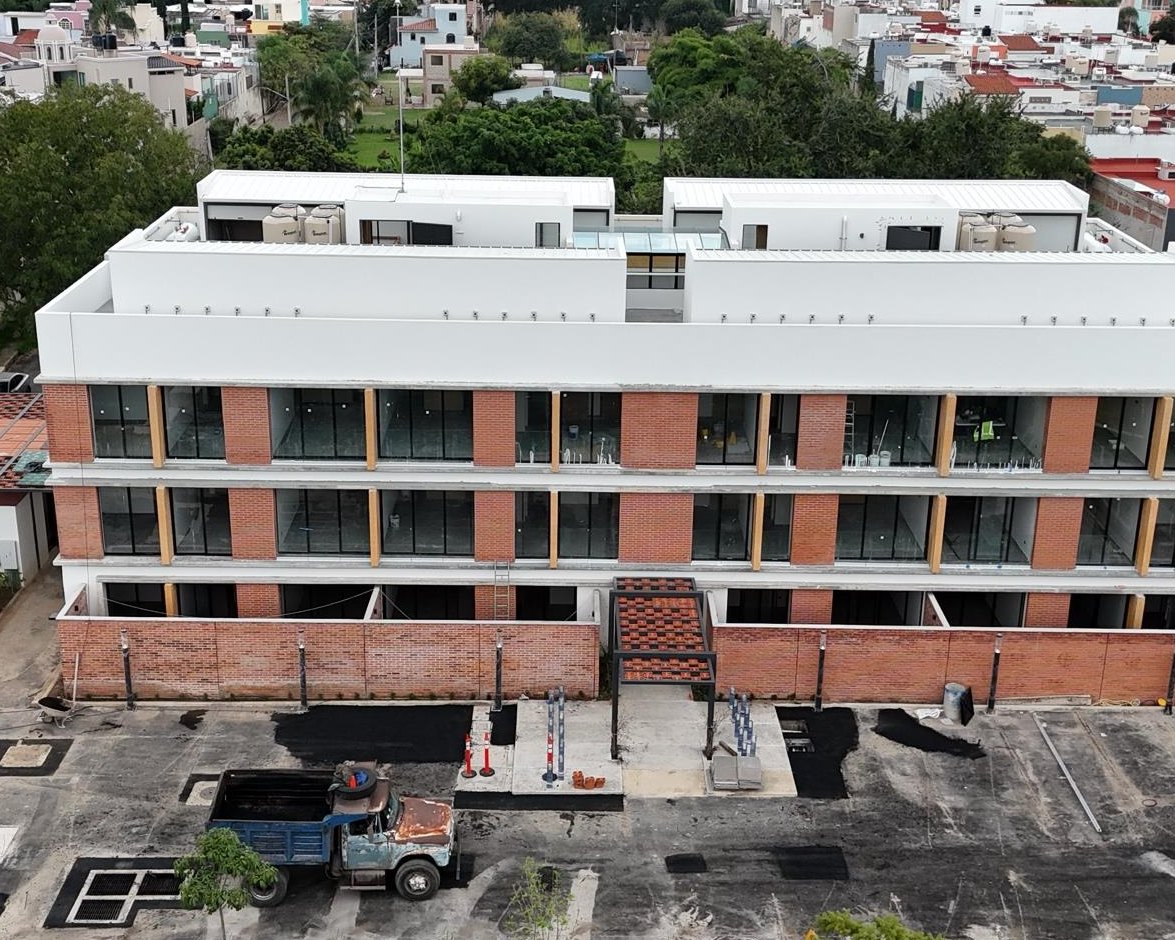 Vista aérea de la obra de Privada Zalate: la fachada de tabique y ventanales ya terminada, con el barrio de fondo