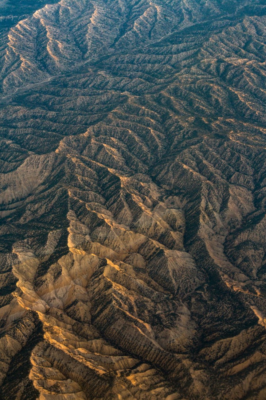 Vista aérea de un relieve montañoso, con luz rasante marcando cada cresta y quebrada